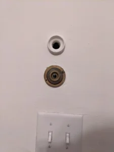 I am on the second floor of an old house in the northeast USA. There is another one at the entrance to the second floor, this at the backdoor. The button looks like a bell but what is the hole for?